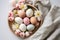 Modern Easter flat lay. Beautiful easter eggs in plate, blooming flowers and napkin on table. Pastel Easter wallpaper, holiday