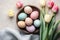 Modern Easter flat lay. Beautiful easter eggs in plate, blooming flowers and napkin on table. Pastel Easter wallpaper, holiday