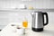 Modern electric kettle, cups of tea and honey on table in kitchen