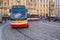 A modern electric tram rounds a corner on the cobbled streets of the old town district of Prague