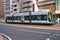 A modern, electric tram waits at junction in the middle of downtown Hiroshima, Japan