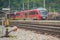 Modern electrical train  with red engine on track on a suburban station. Passenger train rushing towards the city in a suburban