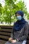 Modern european muslim woman wearing surgical face mask praying digital tespih in the park