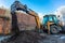 The modern excavator performs excavation work on the construction site. Front view of a digger bucket of digging ground