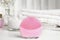 Modern face cleansing brush on table. Cosmetic accessory