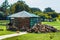 Modern farm with a beautiful lawn and a firewood shed. the logs lie neatly under the canopy. near a pile of ribbed wood