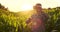 Modern farmer in VR helmet controls corn crop standing in field at sunset in sunlight