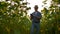 Modern farmer walks with a tablet computer studying sunflowers at sunset. Keep records of the farm. Internet