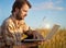 Modern farmer on wheat field with laptop