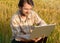 Modern farmer on wheat field with laptop