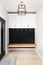 A modern farmhouse entryway with a cabinet and light hanging above.