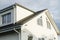 Modern farmhouse exterior with stylish black roof, white walls and windows, dormer and wooden rafters. House facade insulation