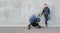 Modern father with newborn stroller standing near gray concrete wall and looking left on copy space. Full length portrait of