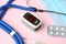 Modern fingertip pulse oximeter and medical items on background