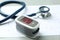 Modern fingertip pulse oximeter, stethoscope and cardiogram on grey table