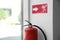 Modern fire extinguisher and emergency exit sign near window