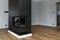 A modern fireplace with a closed combustion chamber standing in the living room, painted black, with a corner pane covered with so