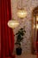 Modern French interior with corduroy burgundy curtains, vintage gold mirror and crystal chandeliers against a brick wall. Soft