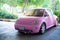 Modern fun pink small car. Photo of a modern funky pink car parked close to the sea and beach huts.