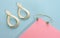Modern golden bracelet and infinity shape golden earrings on pink and blue background