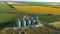 Modern grain silos at the field of blooming sunflowers