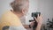 Modern grandfather, an elderly male blogger sets up a camera on smartphone to create video content for vlog in his room