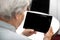 Modern grandma looking at the desk from a tablet, elderly women