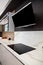 Modern gray white lacquer wood kitchen cabinet and black electric stove and hood on white granite countertop