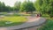 Modern green park. Two young men skateboarding on a wavy road.