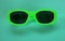 Modern green sunglasses isolate on a green background.Traveler and summer accessories