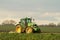 Modern green tractor hedge cutting last years crops