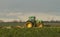 Modern green tractor hedge cutting last years crops