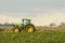 Modern green tractor hedge cutting last years crops