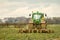 Modern green tractor hedge cutting last years crops