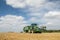 Modern green tractor pulling a trailer in harvest field