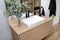 A modern hanging cabinet with a washbasin in the bathroom with a matte black faucet, a visible mirror and artificial flowers.