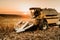 Modern harvesting details with combine harvester and transporting harvest at sunset. Agriculture industry machinery