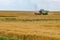 Modern heavy harvester removes the ripe wheat bread in field. Seasonal agricultural work