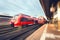 Modern high speed red passenger trains at sunset. Railway station