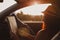 Modern hipster girl resting in a car and reading a map. Woman with feet on car door. Feet outside the window at sunset