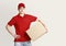 Modern home delivery. Courier in red uniform holds parcel under his arm and waits for customer