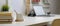 Modern home office desk with coffee cup, books, mock-up laptop, camera and decorations