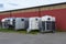 Modern horse transportation trailers parked on the grass near red scandinavian swedish hangar shed house