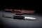 A modern hunting knife and a leather case for him on a dark background. Melee weapons for hunting and self-defense. The instrument