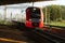 Modern intercity high speed train under the bridge at sunset. Commercial suburban transportation.