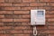 Modern intercom system with handset on red brick wall, space for text