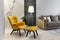 Modern interior design of a living room with a mustard chair, a floor lamp and personal accessories.