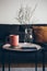 Modern interior details. Little round table with ceramic red color cup of delicious earl gray tea. Resting after work day at home