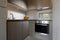 Modern interior of small corner kitchen with white subway brick tile splashback. Fruit plate on light wooden cabinets background