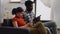Modern interracial people holding smartphones on couch